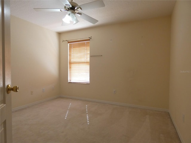 empty room with a ceiling fan, light colored carpet, a textured ceiling, and baseboards