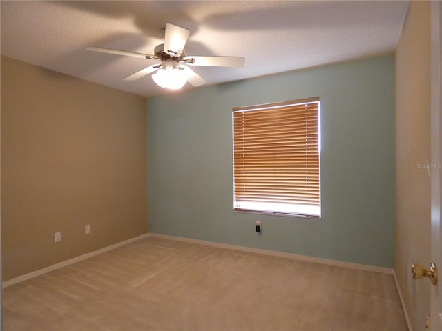 empty room featuring ceiling fan, light colored carpet, and baseboards