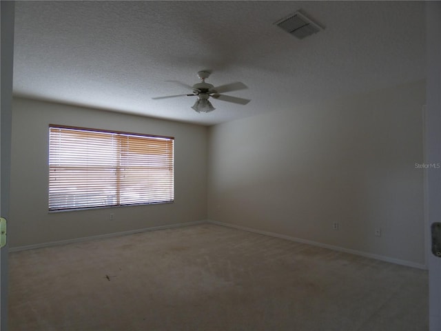 unfurnished room featuring light carpet, visible vents, ceiling fan, and a textured ceiling