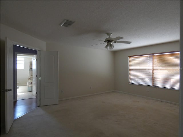 spare room featuring baseboards, visible vents, a textured ceiling, and light colored carpet