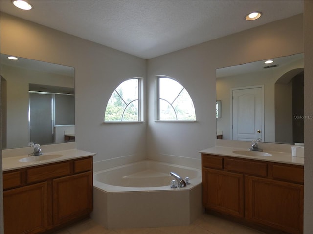 bathroom with a garden tub, a stall shower, a sink, and tile patterned floors