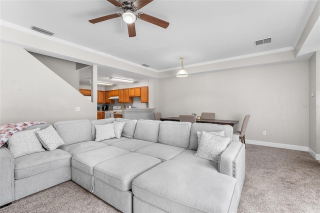 living area with light carpet, baseboards, visible vents, and crown molding