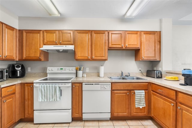 kitchen featuring brown cabinets, light countertops, a sink, white appliances, and under cabinet range hood