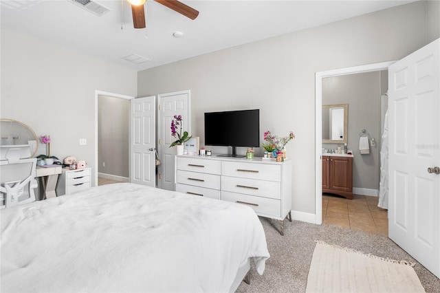 bedroom featuring light carpet, a ceiling fan, visible vents, baseboards, and ensuite bath