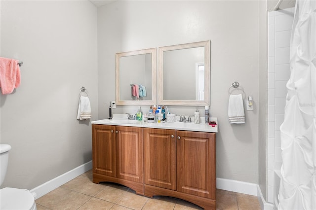 bathroom with toilet, a sink, baseboards, tile patterned floors, and double vanity