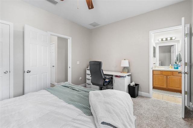 bedroom featuring baseboards, ensuite bath, visible vents, and light colored carpet