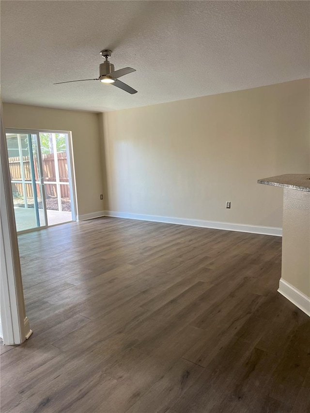 unfurnished room with baseboards, dark wood-type flooring, a ceiling fan, and a textured ceiling