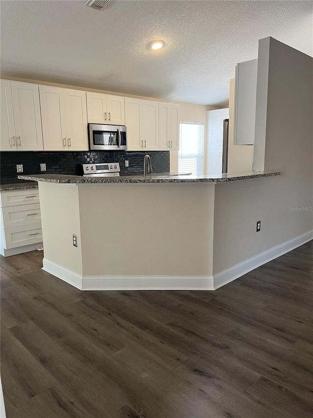 kitchen featuring dark stone countertops, white cabinets, dark wood-style flooring, and stainless steel appliances