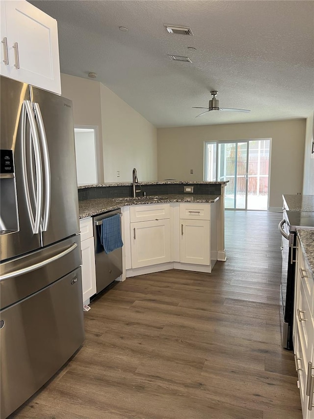 kitchen with visible vents, a sink, stainless steel appliances, white cabinetry, and dark wood-style flooring