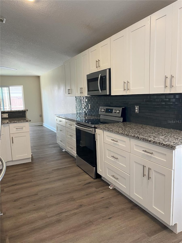 kitchen featuring white cabinets, tasteful backsplash, dark wood-style flooring, and stainless steel appliances