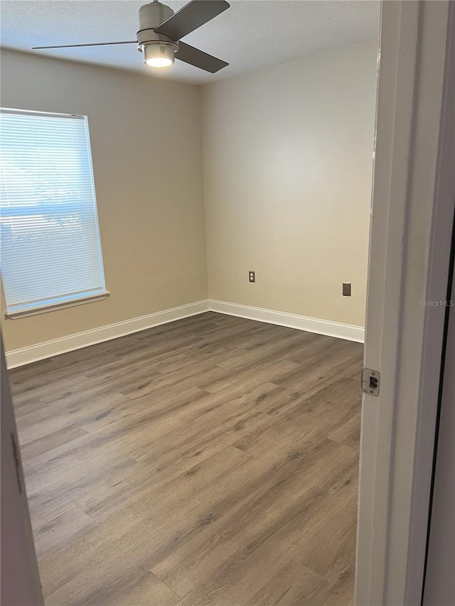 spare room with ceiling fan, wood finished floors, and baseboards
