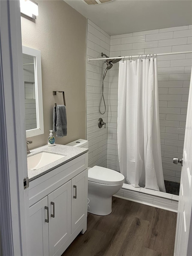 bathroom featuring toilet, vanity, a shower stall, and wood finished floors