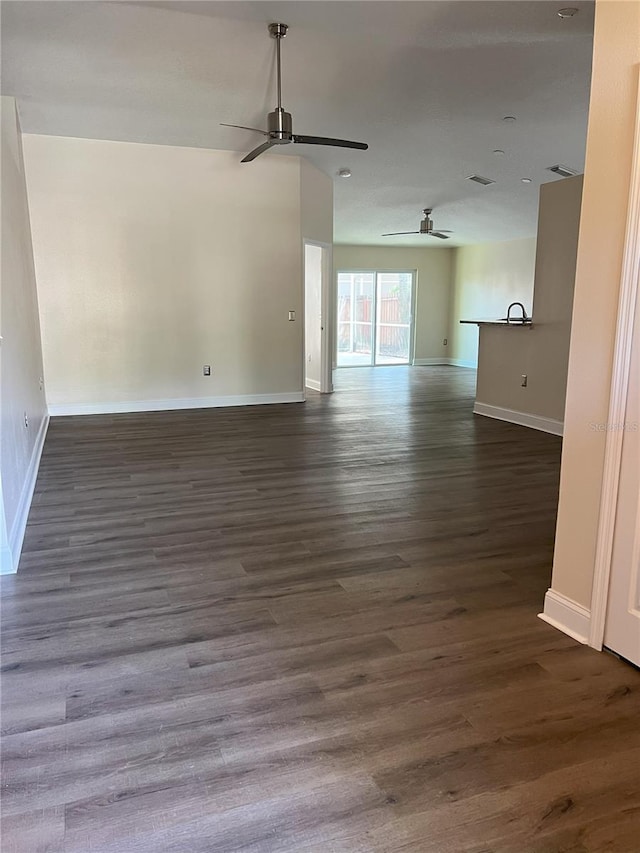 unfurnished room with dark wood-type flooring, a ceiling fan, and baseboards