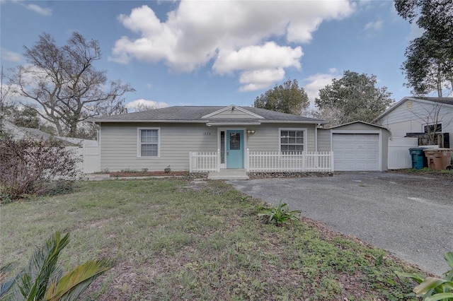 single story home with a garage, driveway, an outbuilding, fence, and a front yard