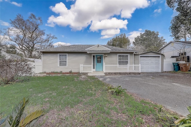 ranch-style house featuring aphalt driveway, a front yard, an outdoor structure, and fence