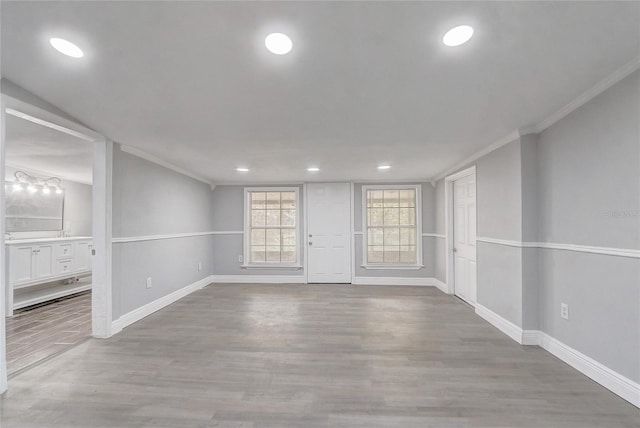 spare room featuring baseboards, wood finished floors, and crown molding