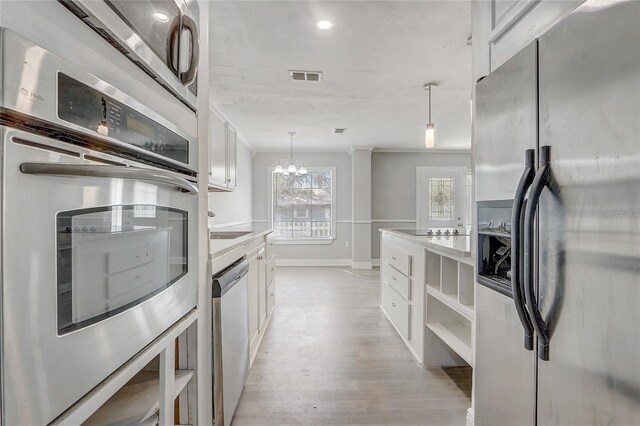 kitchen with decorative light fixtures, stainless steel appliances, visible vents, light wood-style floors, and white cabinetry