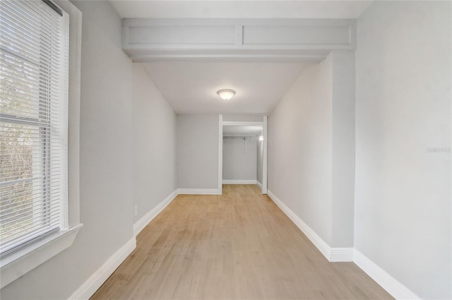 corridor with light wood finished floors, a wealth of natural light, and baseboards