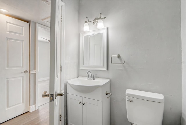 bathroom featuring toilet, wood finished floors, and vanity