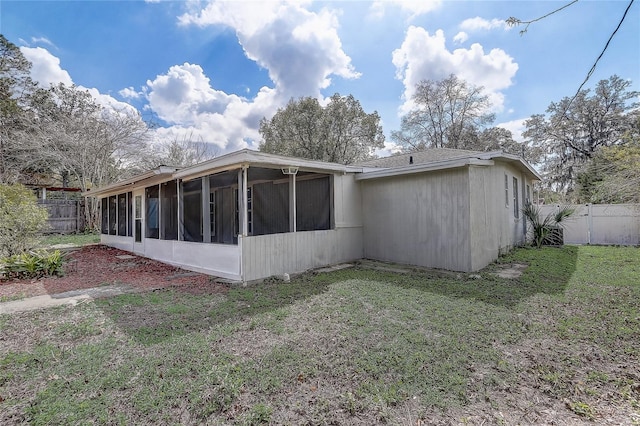 rear view of house featuring a lawn, fence, and a sunroom