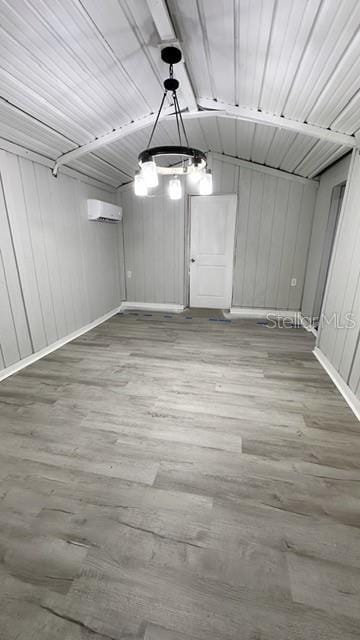 below grade area with wood finished floors and a wall unit AC