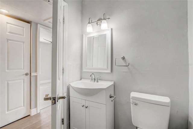 half bath featuring vanity, toilet, and wood finished floors