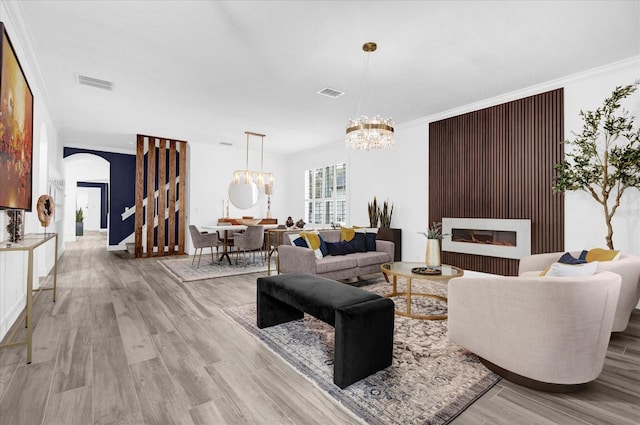 living room featuring light wood-type flooring, arched walkways, visible vents, and a notable chandelier