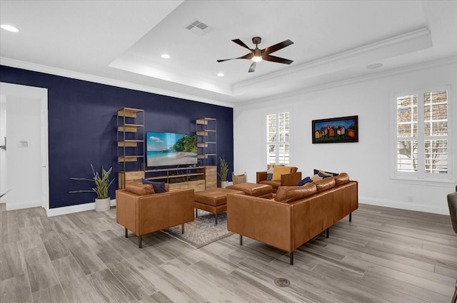 living area featuring a tray ceiling, visible vents, baseboards, and wood finished floors