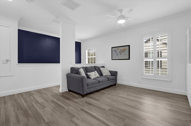 living area featuring ornamental molding, visible vents, light wood-style flooring, and a ceiling fan