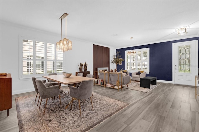 dining area featuring a notable chandelier, light wood-type flooring, baseboards, and crown molding