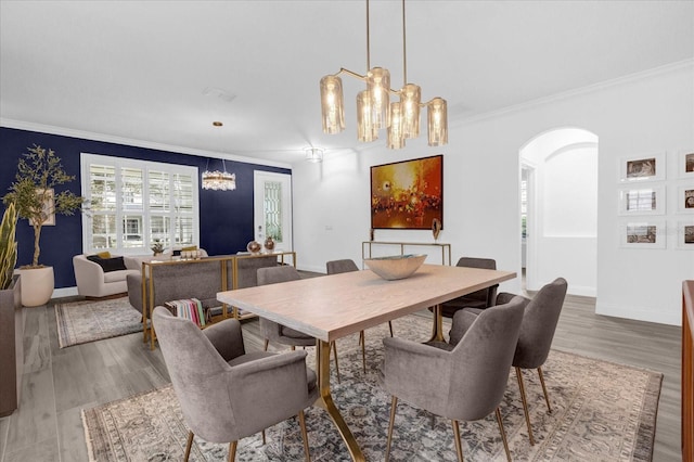 dining area with arched walkways, crown molding, baseboards, and wood finished floors