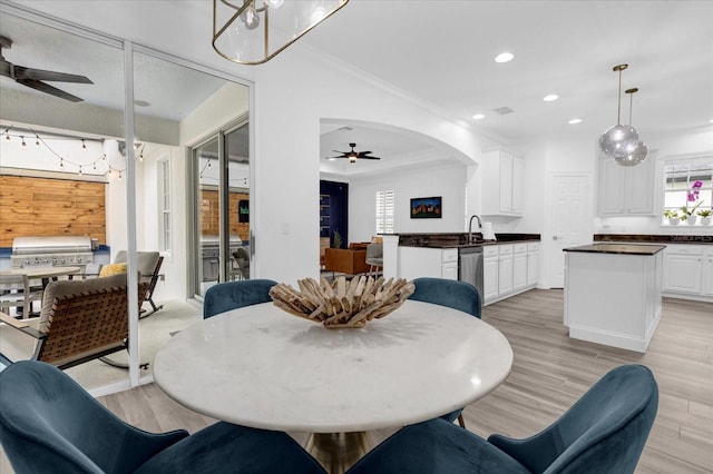 dining space featuring arched walkways, ceiling fan, crown molding, light wood-type flooring, and recessed lighting