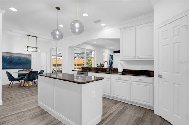 kitchen featuring pendant lighting, white cabinetry, a sink, and visible vents