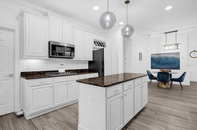 kitchen with stainless steel appliances, decorative light fixtures, white cabinetry, and a center island