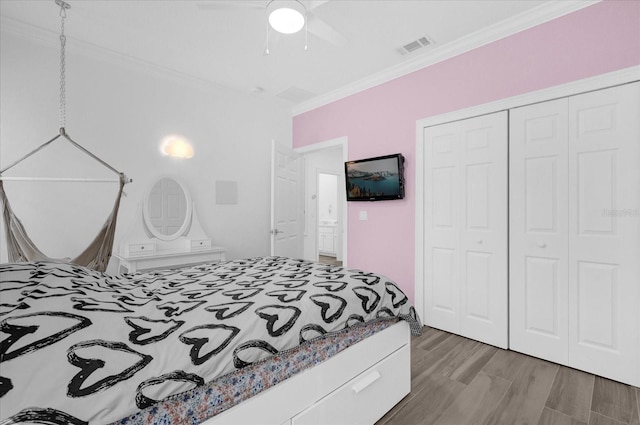 bedroom featuring visible vents, a ceiling fan, wood finished floors, crown molding, and a closet