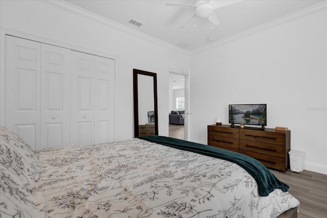 bedroom with ceiling fan, wood finished floors, visible vents, a closet, and crown molding