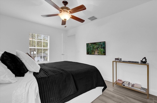 bedroom featuring light wood-style floors, baseboards, visible vents, and a ceiling fan