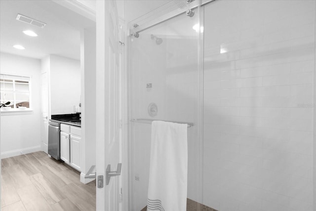 full bathroom featuring visible vents, a walk in shower, wood finished floors, and vanity