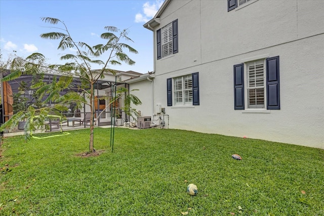 exterior space with a lanai, a yard, and stucco siding