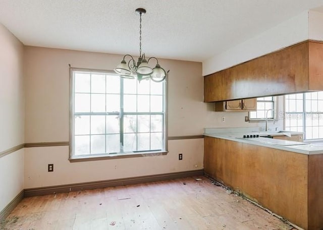 106 Thurston Pl, Crestview, FL 32536 - kitchen with a chandelier, healthy amount of natural light, light wood finished floors, brown cabinets, and a textured ceiling
