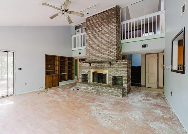 106 Thurston Pl, Crestview, FL 32536 - unfurnished living room featuring a towering ceiling, ceiling fan, rail lighting, a fireplace, and baseboards