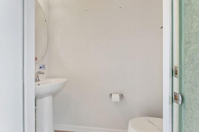 bathroom with a sink, toilet, and baseboards