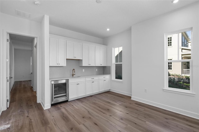 kitchen with beverage cooler, light countertops, tasteful backsplash, and white cabinets