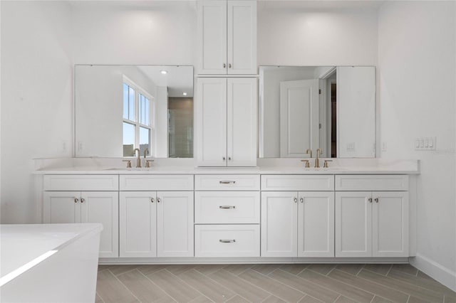 full bathroom with a sink, baseboards, and double vanity