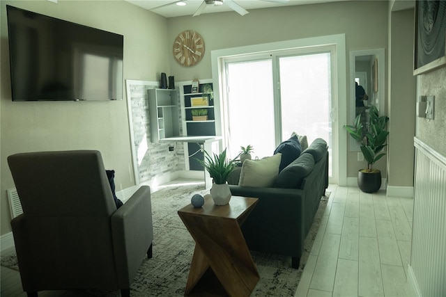 living area featuring baseboards, a ceiling fan, and wood finished floors