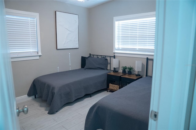 bedroom with multiple windows and light wood finished floors