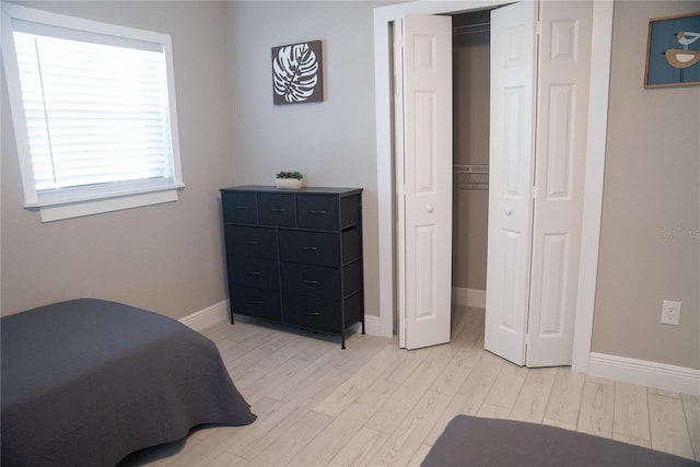 bedroom featuring light wood-style flooring, baseboards, and a closet