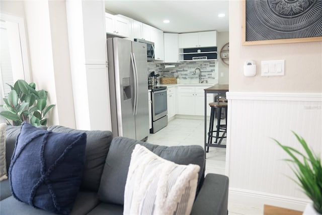 kitchen with white cabinets, stainless steel appliances, a sink, and open floor plan