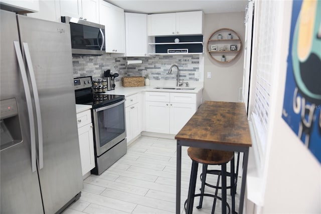 kitchen featuring white cabinets, tasteful backsplash, stainless steel appliances, and a sink