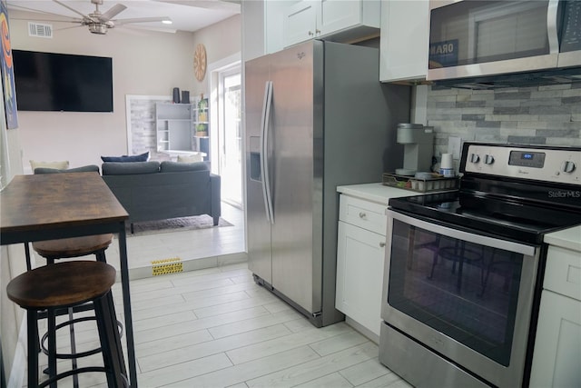 kitchen with stainless steel appliances, light countertops, visible vents, and tasteful backsplash